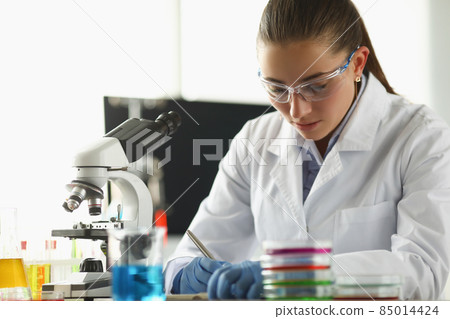 Concentrated chemist worker write down thoughts on investigation project in lab Concentrated chemist worker write down thoughts on investigation project in lab 85014424
