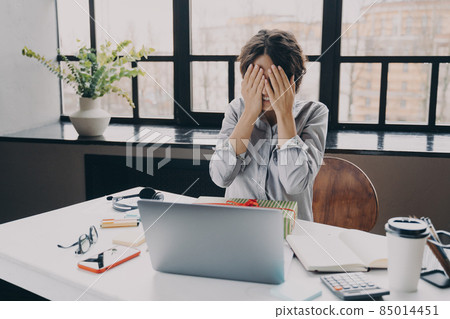 Curious woman office employee covering eyes with hands while getting x-mas present at work 85014451