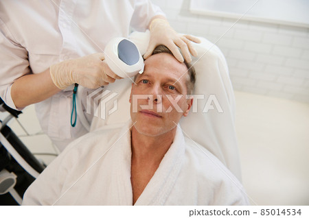 Handsome mature European man receives a facial contouring procedure with meso threads for face rejuvenation, anti-aging, facelift, mesotherapy procedures at the wellness spa. Male cosmetology concept Handsome mature European man receives a facial contouring procedure with meso threads for face rejuvenation, anti-aging, facelift, mesotherapy procedures at the wellness spa. Male cosmetology concept 85014534