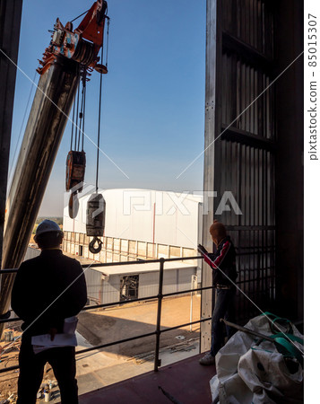 Hoist of crane at the window of industrial plant 85015307