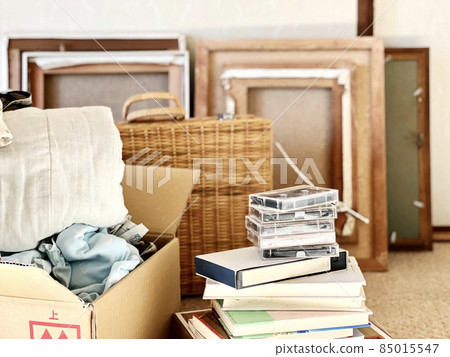 Videotapes, cassette tapes, cardboard and some picture frames stacked on top of books Videotapes, cassette tapes, cardboard and some picture frames stacked on top of books 85015547