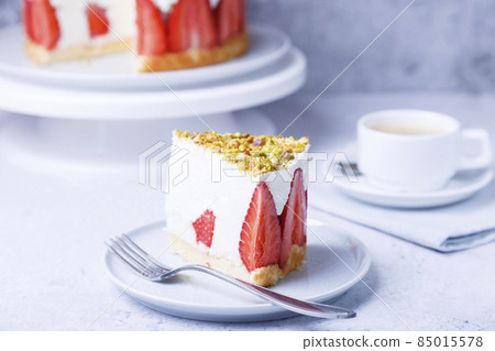 Freesier cake with fresh strawberries and pistachios. French classic dessert. Portion of cake on a white plate close-up. 85015578