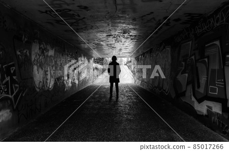 Young woman standing in a concrete tunnel Young woman standing in a concrete tunnel 85017266