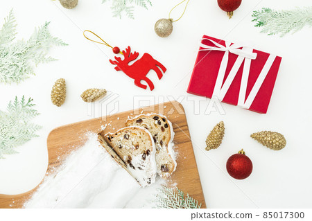 Christmas composition with stollen cake on wooden board, tree toys and gift on white. Flat lay Christmas composition with stollen cake on wooden board, tree toys and gift on white. Flat lay 85017300