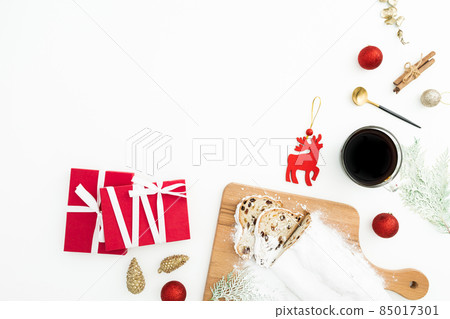 Christmas composition with stollen cake on a wooden board with coffee cup, tree toys and gift on white. Flat lay. Cpoy space 85017301