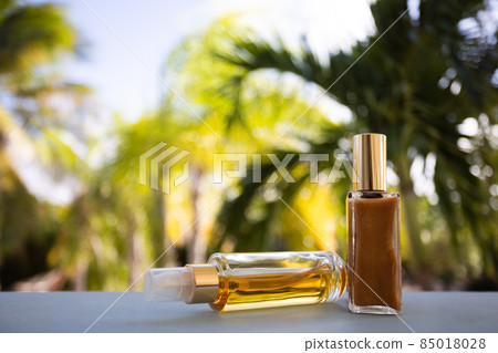 Small bottles of cosmetic liquids on a palm leaves background. Selective focus. Small bottles of cosmetic liquids on a palm leaves background. Selective focus. 85018028