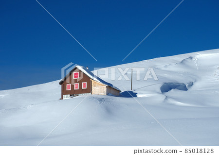 Winter landscape in the Swiss mountains: A beautiful hut on a snow covered mountains under the deeply blue sky Winter landscape in the Swiss mountains: A beautiful hut on a snow covered mountains under the deeply blue sky 85018128