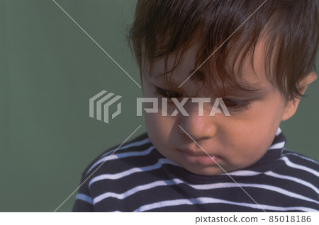 Beautiful Cute sad looking Baby in Chin down posture. Bored face, Lonely boy leaning his head down in deep thought, Upset, unhappy and sad. Close up. Indian ethnicity. Headshot portrait. Isolated 85018186