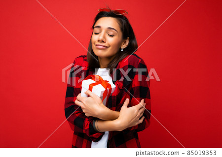 Pretty positive cute young brunette woman isolated over red background wall wearing white casual t Pretty positive cute young brunette woman isolated over red background wall wearing white casual t 85019353