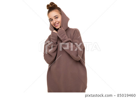 Photo of a beautiful cute smiling girl with dark hair and a bun in a brown hoodie with a hood Photo of a beautiful cute smiling girl with dark hair and a bun in a brown hoodie with a hood 85019460
