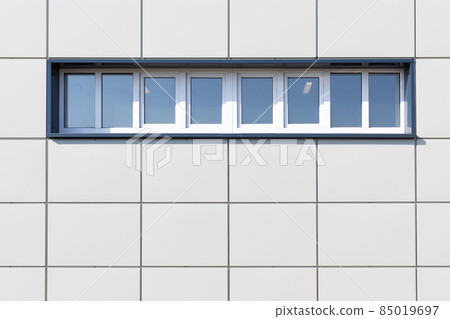 Photo of a white wall of a house with squares and small windows on the street 85019697