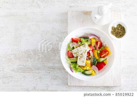 Fresh summer vegetable salad with lettuce, tomato, cucumber, bell pepper, onion and feta cheese, dressed with olive oil. Top view Fresh summer vegetable salad with lettuce, tomato, cucumber, bell pepper, onion and feta cheese, dressed with olive oil. Top view 85019922
