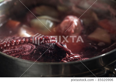 Whole octopus boiling in the the pot filled with water and vegetables. Tentacles of red octopus being boiled Whole octopus boiling in the the pot filled with water and vegetables. Tentacles of red octopus being boiled 85020906