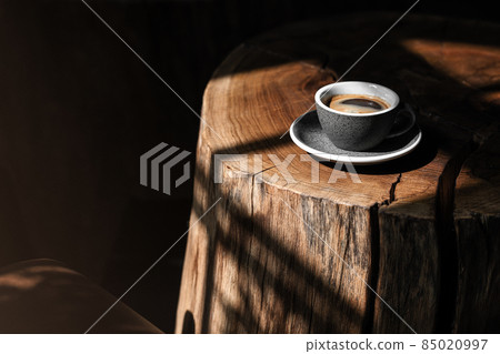 Coffee cup on solid oak stump coffee table. Natural shadows from sunlight Coffee cup on solid oak stump coffee table. Natural shadows from sunlight 85020997