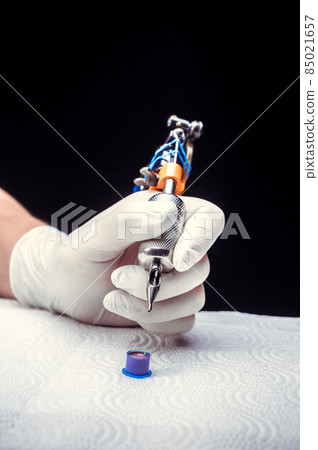 Hand of a tattoo artist with a tattoo gun. Hand of a tattoo artist with a tattoo gun. 85021657