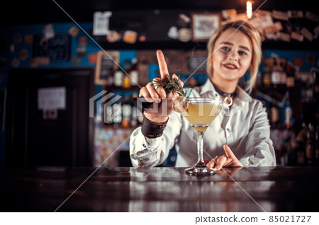 Professional girl bartending demonstrates his professional skills while standing near the bar counter in bar Professional girl bartending demonstrates his professional skills while standing near the bar counter in bar 85021727