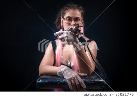 Master tattooist with a tattoo machine in tattoo parlor Master tattooist with a tattoo machine in tattoo parlor 85021776