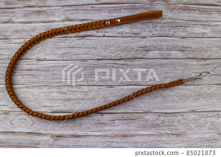 Brown leather leash for dog on wooden background. Top view 85021873