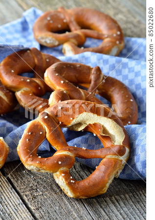 Crunchy fresh Bavarian pretzels on an old wooden table with a tea towel Crunchy fresh Bavarian pretzels on an old wooden table with a tea towel 85022680