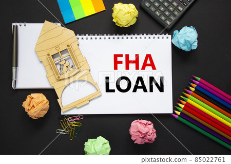 FHA federal housing administration loan symbol. White note with words 'FHA loan' on beautiful black background, metalic pen, calculator, colored pencils, miniature wooden house. Business, FHA concept. FHA federal housing administration loan symbol. White note with words 'FHA loan' on beautiful black background, metalic pen, calculator, colored pencils, miniature wooden house. Business, FHA concept. 85022761