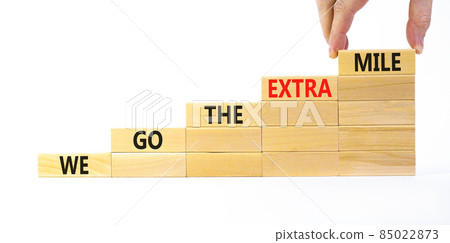 We go the extra mile symbol. Wooden blocks with words We go the extra mile. Beautiful white background, copy space. Businessman hand. Business, we go the extra mile concept. 85022873