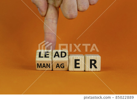 Manager versus leader symbol. Businessman flips wooden cubes and changes the word 'manager' to 'leader'. Beautiful orange background, copy space. Business and manager versus leader concept. 85022889