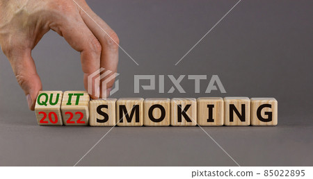 Quit smoking 2022 new years resolution symbol. Businessman turns wooden cubes with words '2022 quit smoking'. Beautiful grey background, copy space. Healthy lifestyle and 2022 quit smoking concept. 85022895