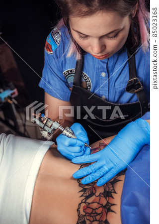 Master tattooist demonstrates the process of getting tattoo in tatoo salon Master tattooist demonstrates the process of getting tattoo in tatoo salon 85023168