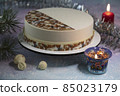 Christmas Eve - a beautiful cake on the table with a pine cone, candle lights, a garland of tinsel and chocolate toys for decorating a mousse cake - a concept for a Christmas card 85023179
