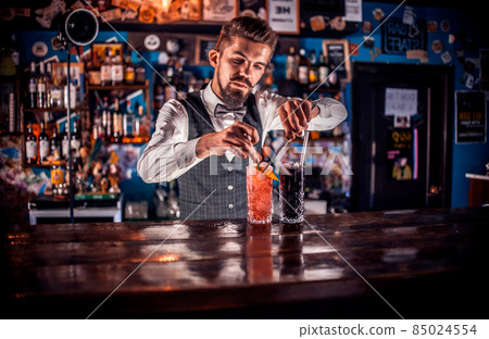 Young bartending mixes a cocktail at bar 85024554