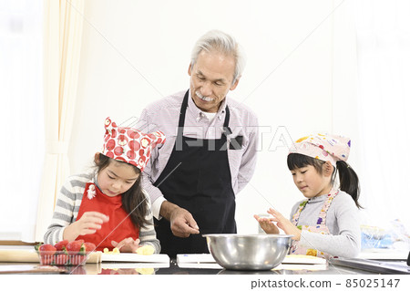 Elementary school girls and senior men learning how to make cakes in a social tour experience class 85025147