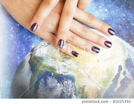 manicure stylish concept: woman fingers with nails purple glitter on nails like cosmos, universe background 85025392