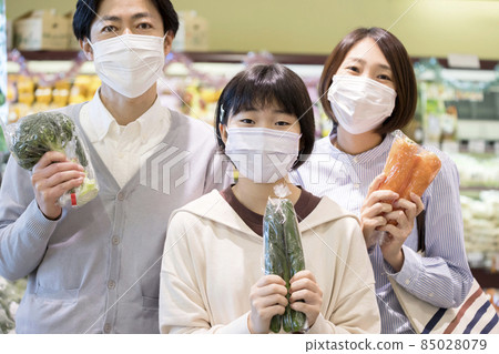 Parents and children in masks holding vegetables at the supermarket Parents and children in masks holding vegetables at the supermarket 85028079