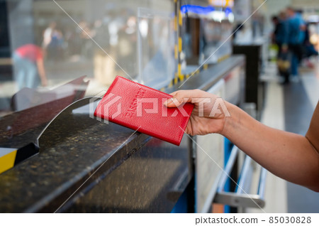 Faceless woman giving her passport at the airport check-in counter. 85030828