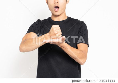 A man wearing a black T-shirt standing in front of a white background and making a convincing pose 85031343