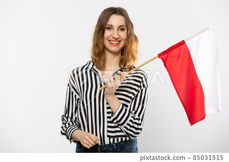 Young girl with a flag of Poland. The student holds the national flag in her hand, the symbol of the Polish state. Woman with flag on white background. Isolated from the background. 85031515