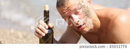 Drunk man on beach with closed eyes holding bottle of wine Drunk man on beach with closed eyes holding bottle of wine 85031778