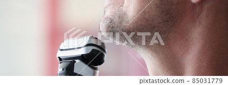 Young man shaves with electric razor closeup Young man shaves with electric razor closeup 85031779