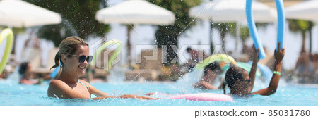 Young woman is engaged in aqua aerobics in outdoor pool Young woman is engaged in aqua aerobics in outdoor pool 85031780