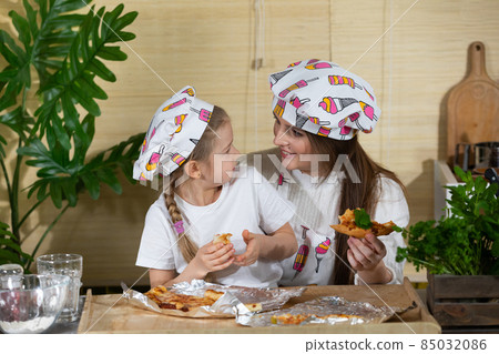 Satisfying yourself with heartfelt words in your ear while eating homemade pizza. Mom and daughter moments together in the home kitchen. 85032086