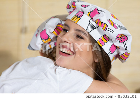 While eating home-made pizza, a five-year-old daughter hugs her mother warmly, thus reciprocating her mother's love for her child. While eating home-made pizza, a five-year-old daughter hugs her mother warmly, thus reciprocating her mother's love for her child. 85032101