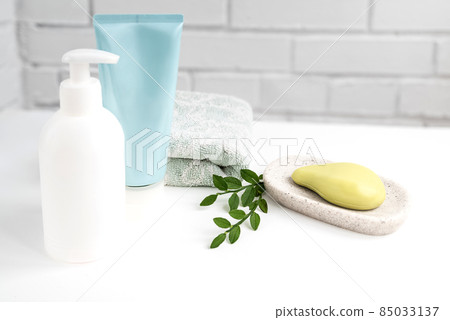 Bathroom interior with fresh towel, organic soap on tray and cosmetic tubes on white table Bathroom interior with fresh towel, organic soap on tray and cosmetic tubes on white table 85033137