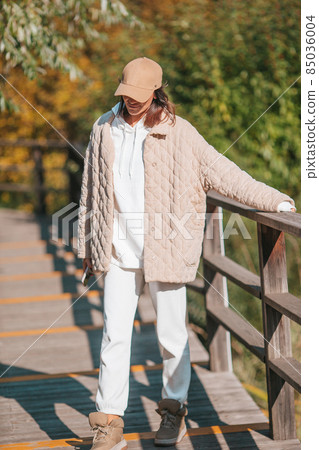 Fall concept - beautiful woman drinking coffee in autumn park under fall foliage Fall concept - beautiful woman drinking coffee in autumn park under fall foliage 85036004