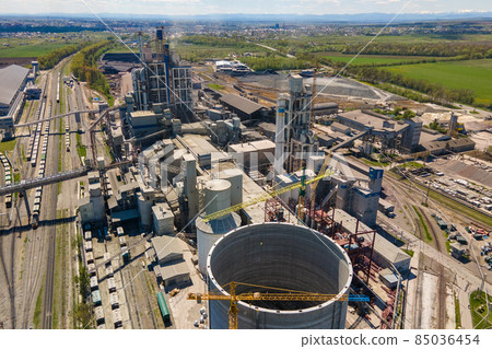 Aerial view of cement factory with high concrete structure and tower crane at industrial production area. Manufacture and global industry concept. Aerial view of cement factory with high concrete structure and tower crane at industrial production area. Manufacture and global industry concept. 85036454