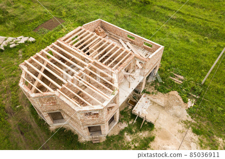 Aerial view of a brick house with wooden ceiling frame under construction. Aerial view of a brick house with wooden ceiling frame under construction. 85036911