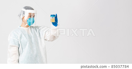 Covid-19, coronavirus disease, healthcare workers concept. Side view of serious-looking tech lab employee, researcher in personal protective equipment examine urine analyzes, white background Covid-19, coronavirus disease, healthcare workers concept. Side view of serious-looking tech lab employee, researcher in personal protective equipment examine urine analyzes, white background 85037784
