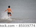 Boy in a swimsuit running towards the sea 85039774