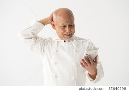 A male chef with a calculator is worried 85040296