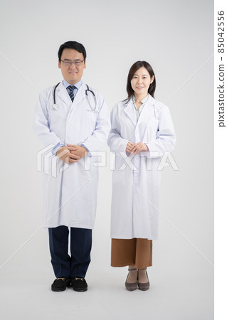 Male and female doctors with hands folded in front, whole body white background 85042556