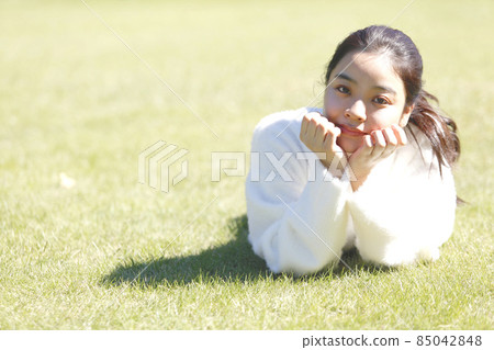 放鬆在草坪的年輕微笑的婦女 放鬆在草坪的年輕微笑的婦女 85042848